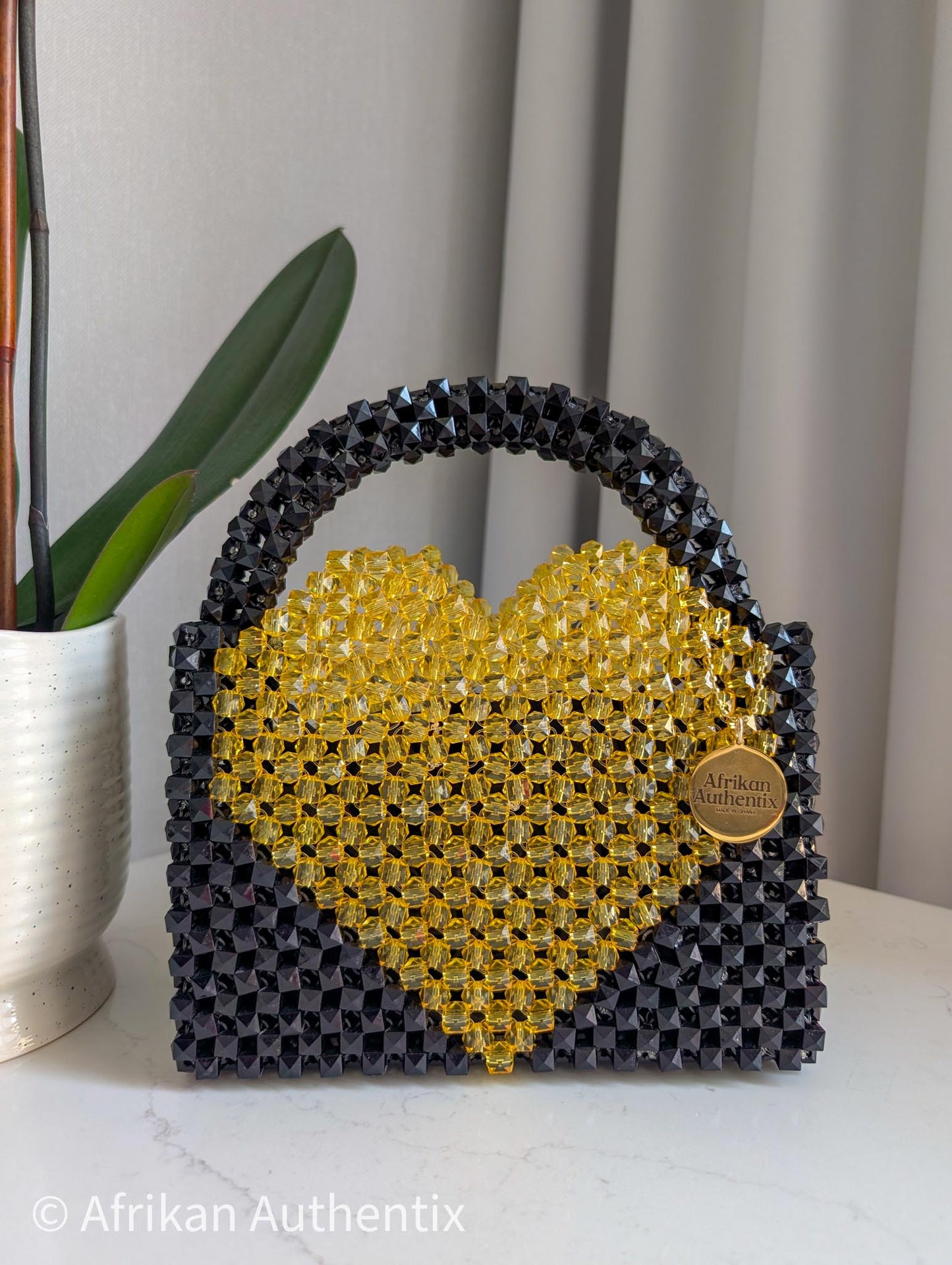 Black and yellow beaded bag with a heart shape bag, featuring the brand 'Afrikan Authentix