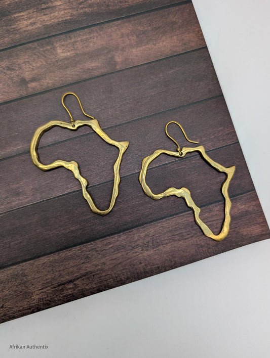 Gold Africa outline earrings on a wooden surface