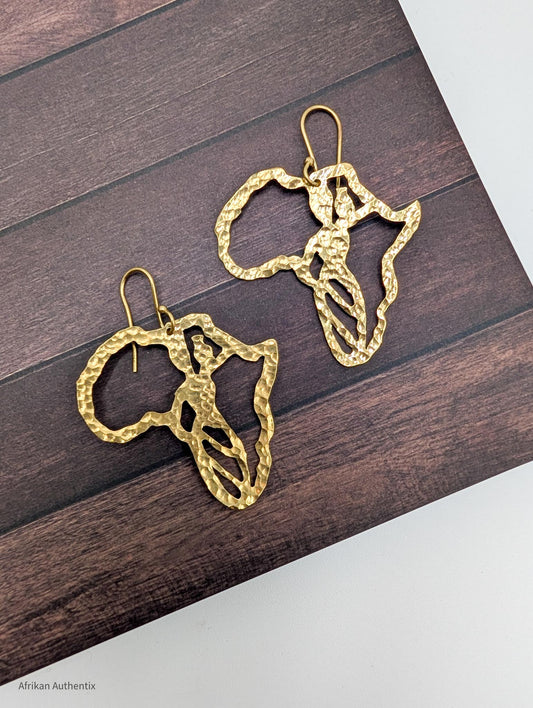 Gold Africa-shaped earrings on a wooden surface