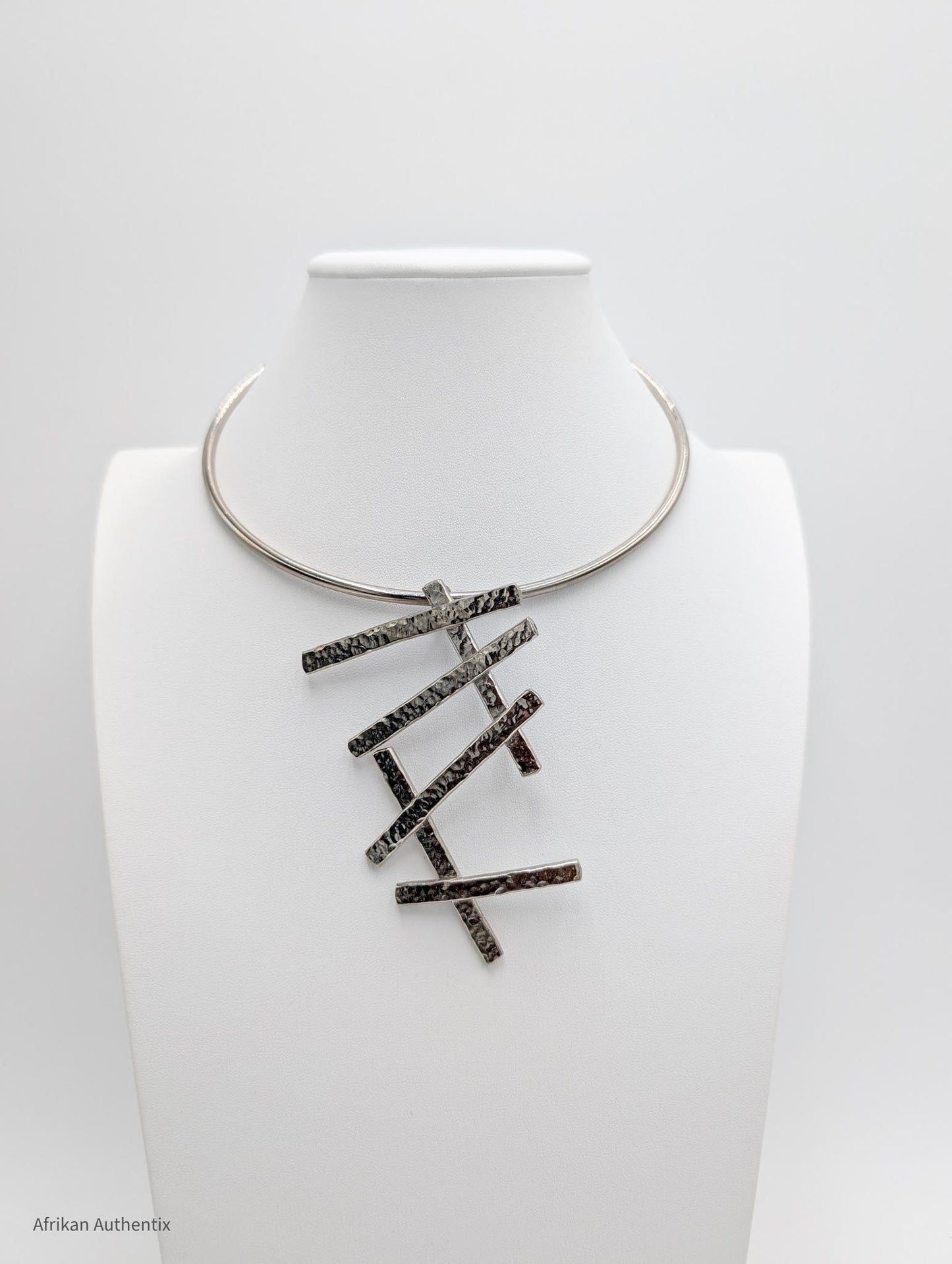 Silver collar necklace with a geometric pendant on a white background