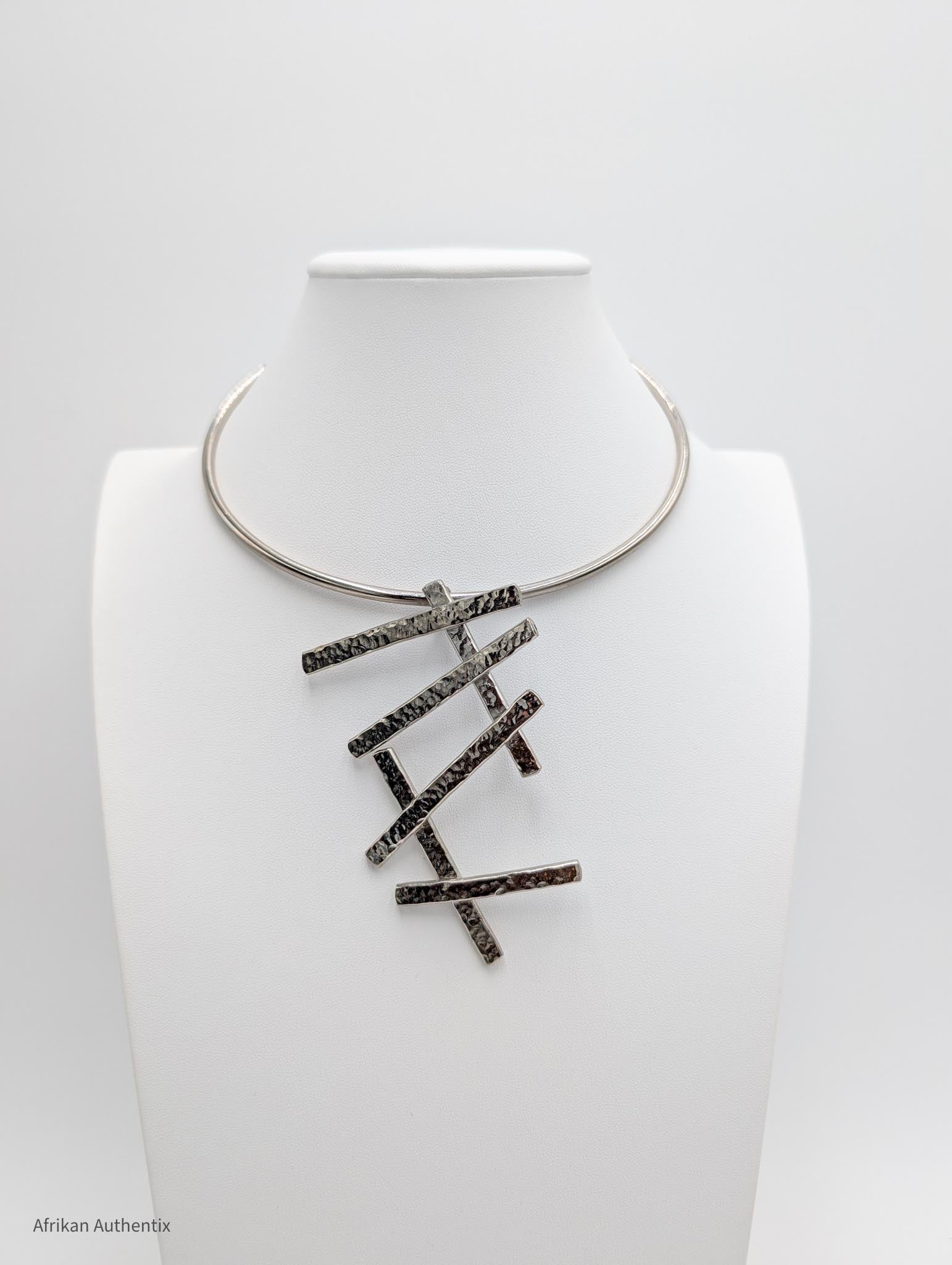 Silver collar necklace with a geometric pendant on a white background