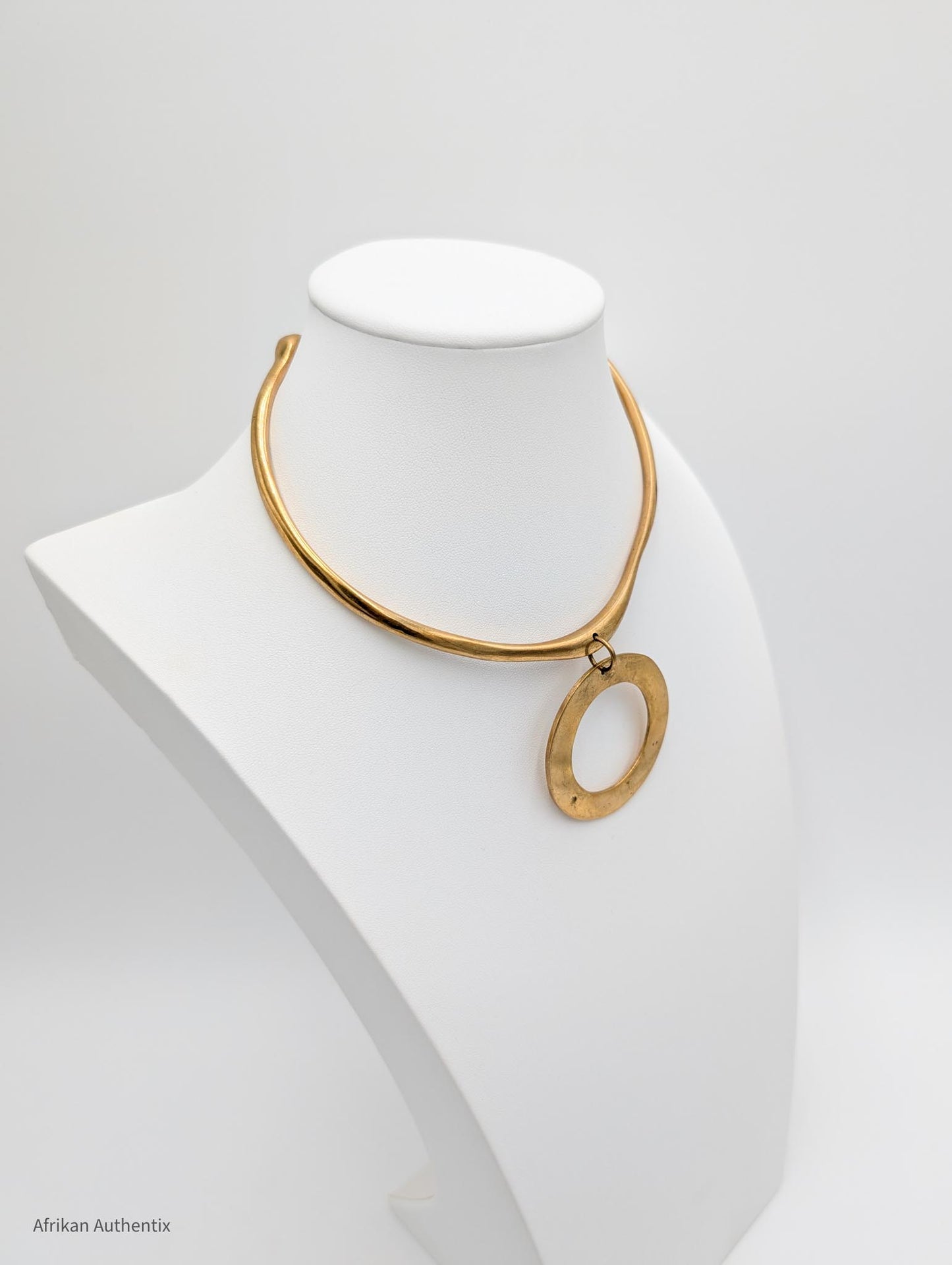 Brass collar necklace on a mannequin bust against a white background
