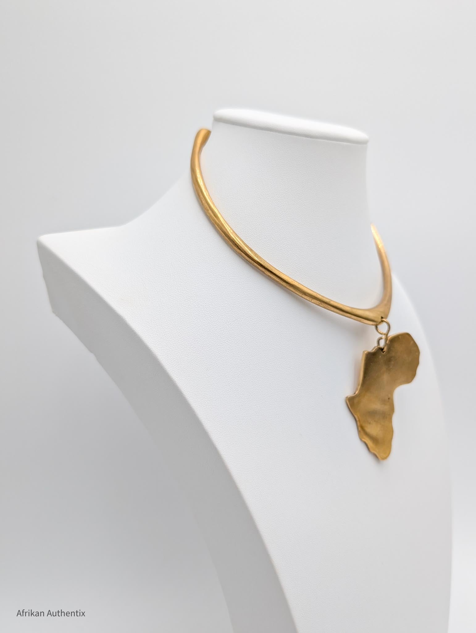 Gold necklace with an africa map pendant on a white mannequin bust.