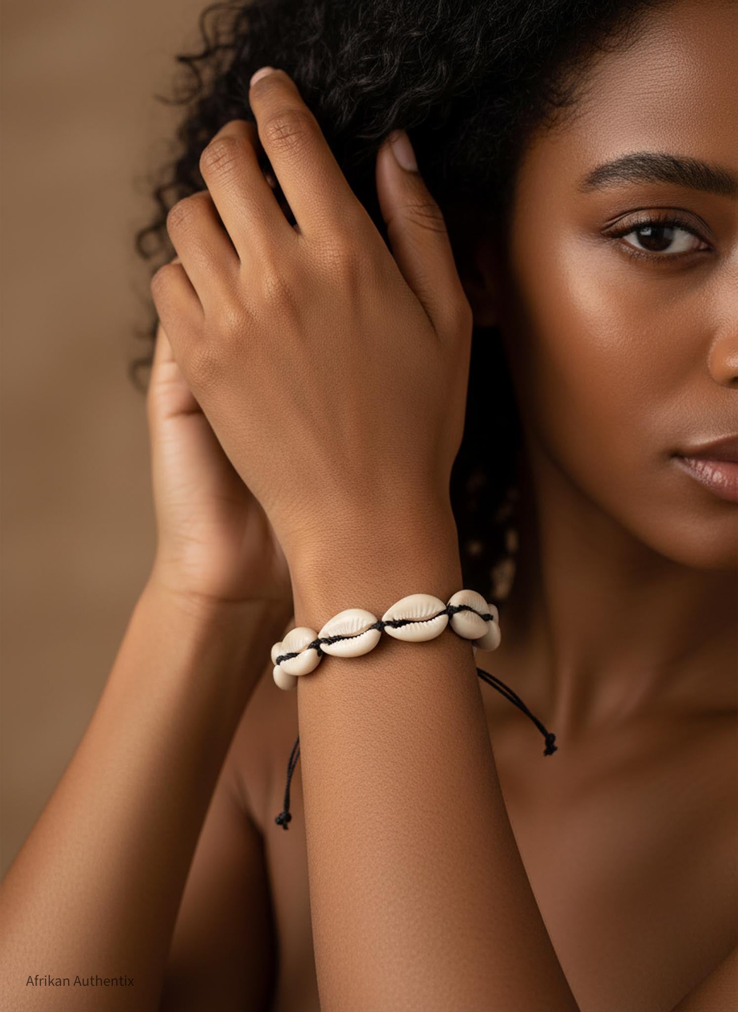 Woman wearing a bracelet with cowrie shells on a brown background