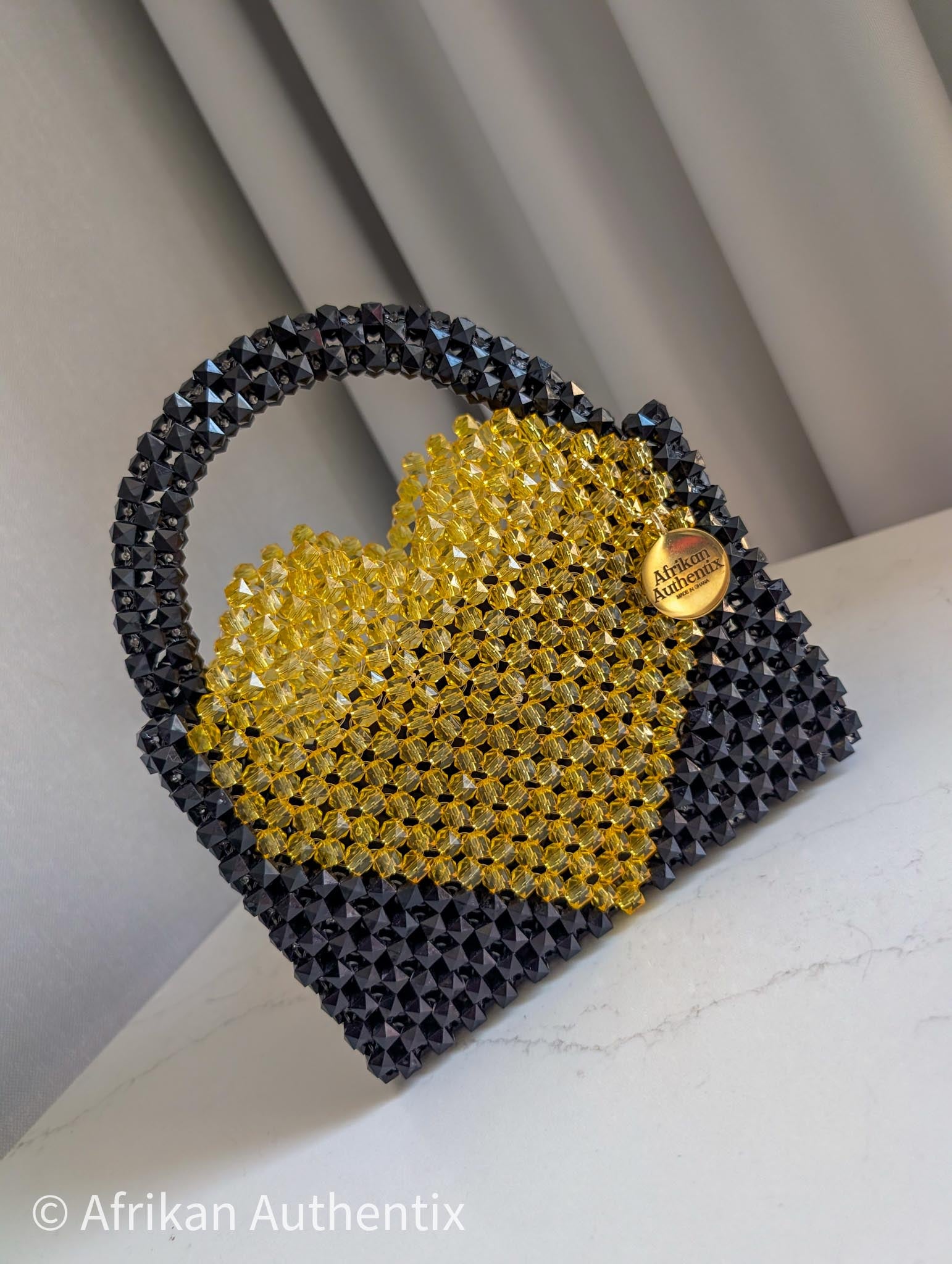 Black and yellow beaded bag with a heart shape bag, featuring the brand 'Afrikan Authentix