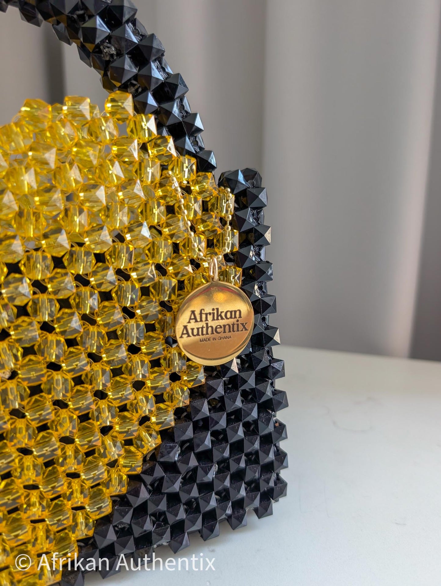 Black and yellow beaded product with 'Afrikan Authentix' logo on a white surface.