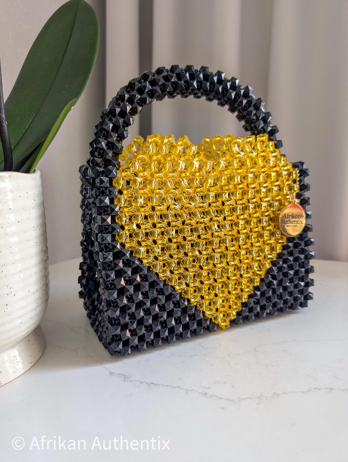 Black and yellow beaded bag with a heart shape bag, featuring the brand 'Afrikan Authentix