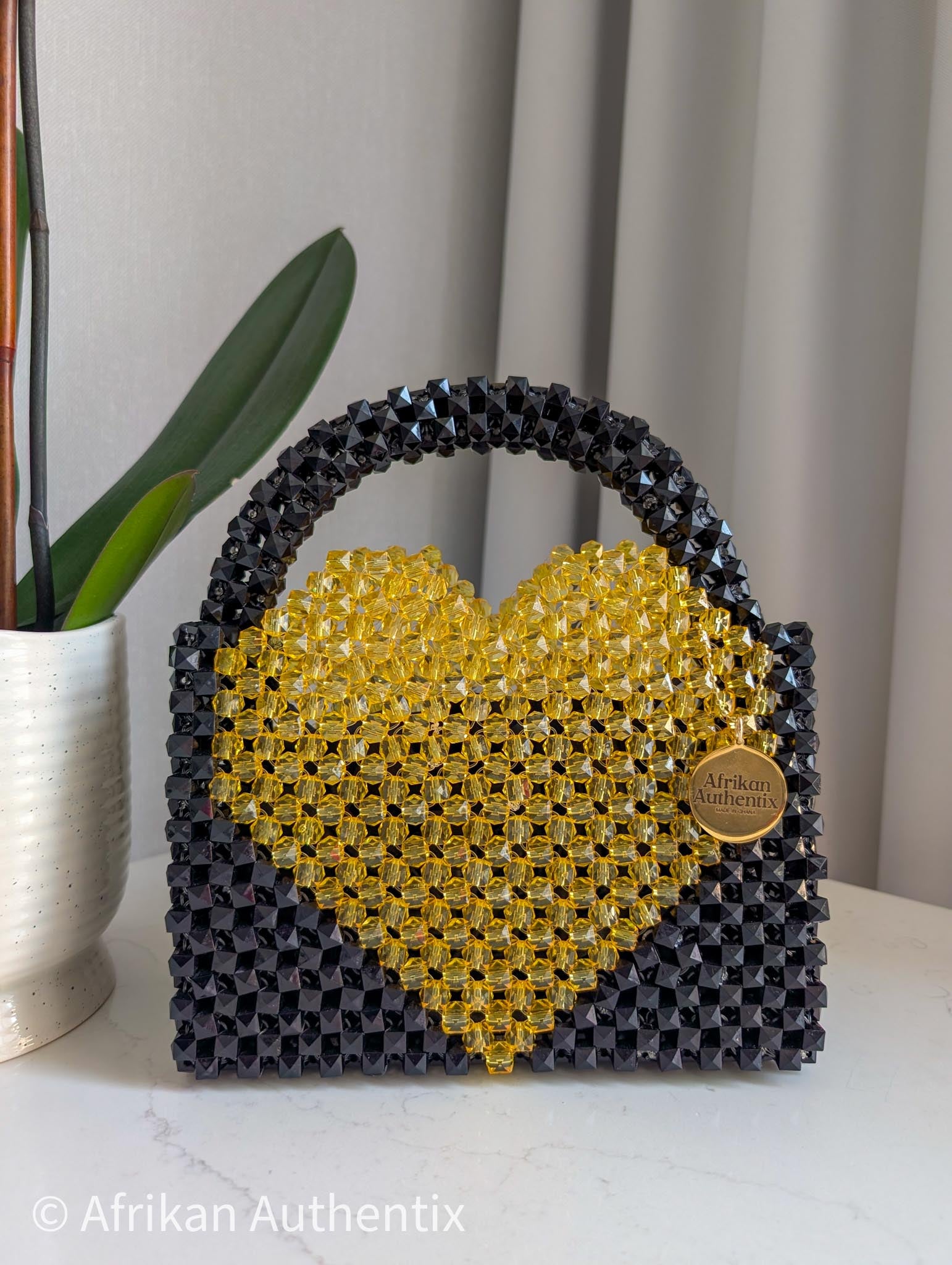 Black and yellow beaded bag with a heart shape bag, featuring the brand 'Afrikan Authentix