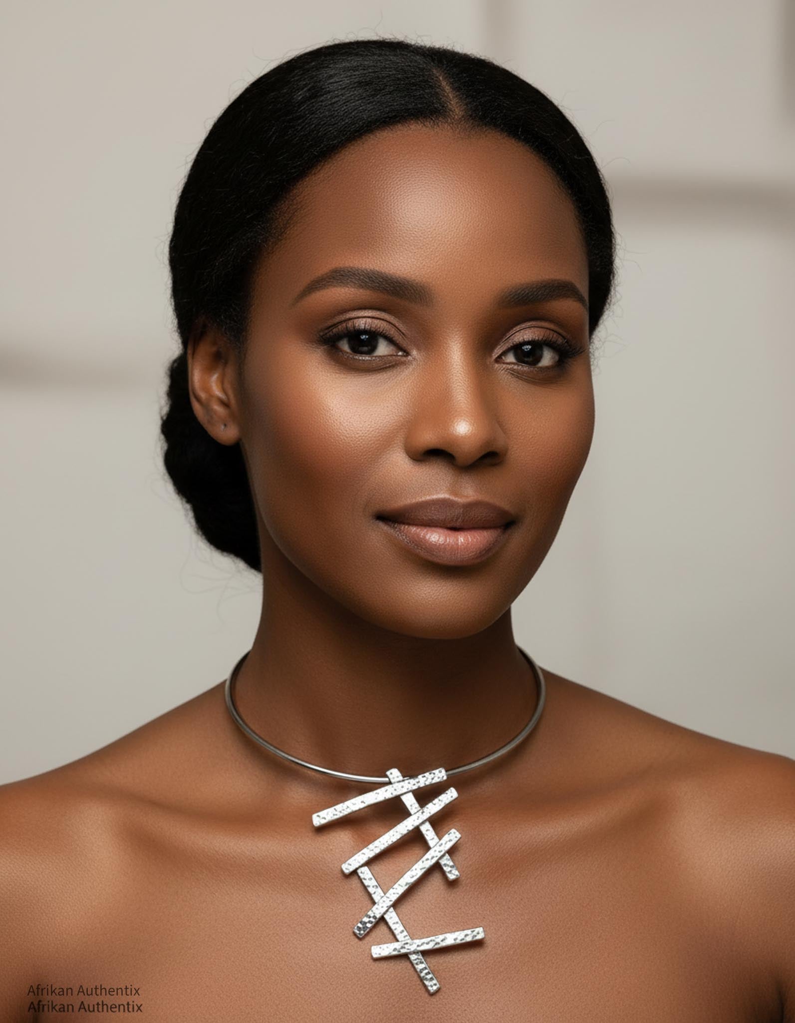 Woman wearing a silver collar necklace with a geometric pendant against a neutral background