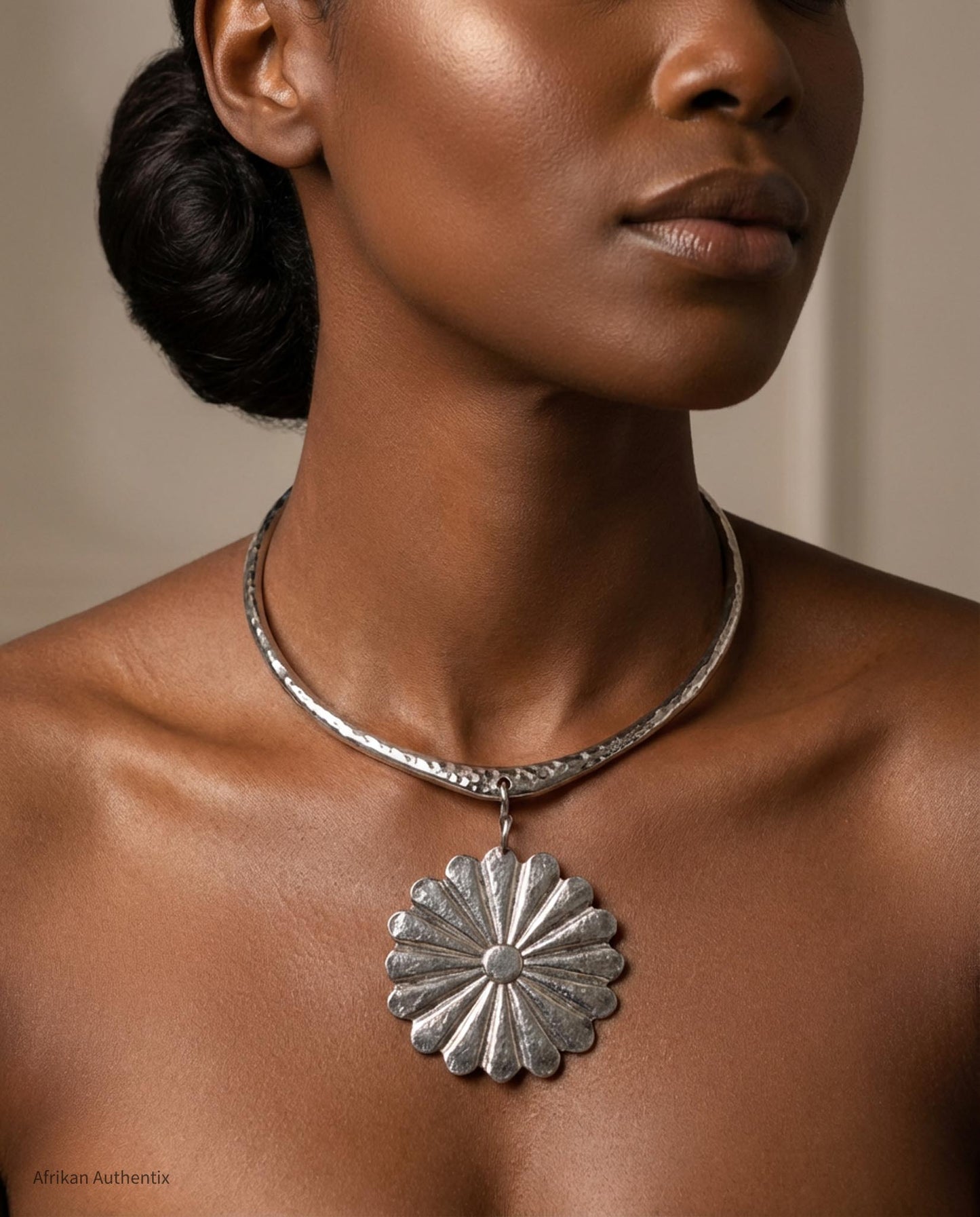 Silver collar necklace with a floral pendant on a person against a neutral background