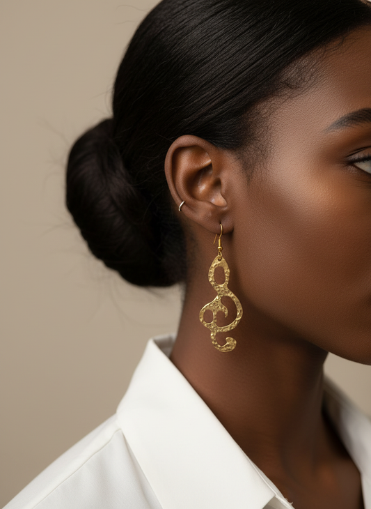 Close-up of a woman wearing Gold treble clef earrings with a neutral background